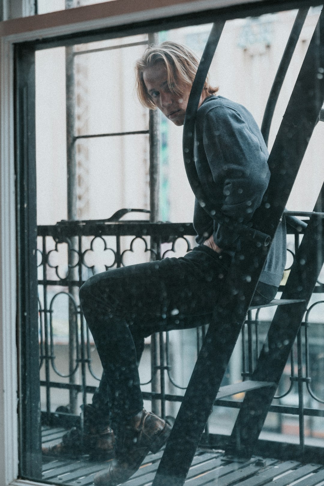 man in blue denim jacket and black pants sitting on black metal frame