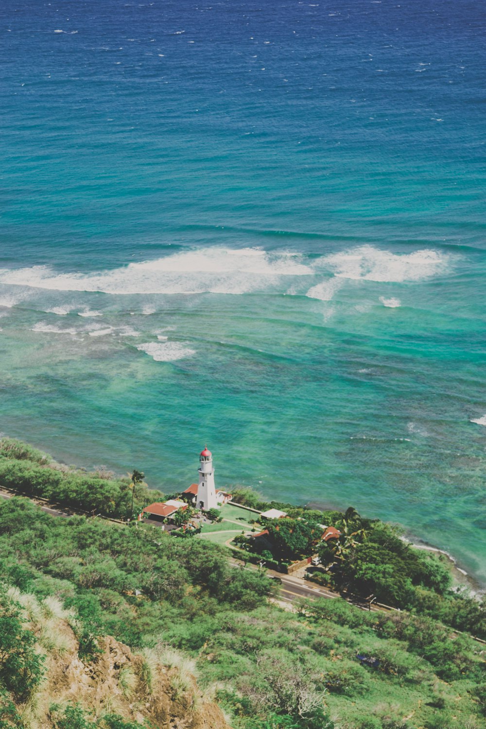 white and red lighthouse on green grass field near body of water during daytime