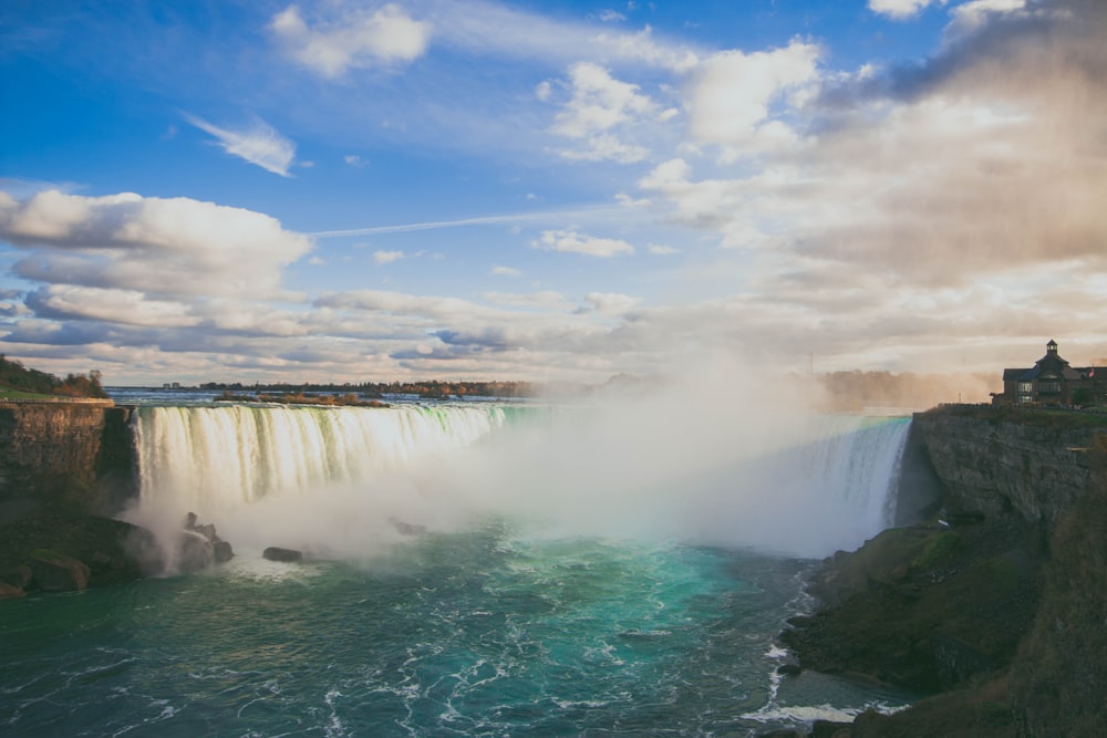 waterfalls under blue sky and white clouds during daytime