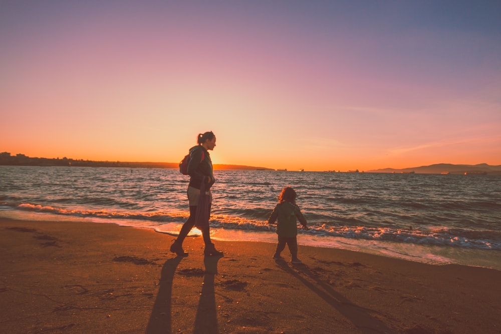 silhueta de 2 pessoas em pé na praia durante o pôr do sol