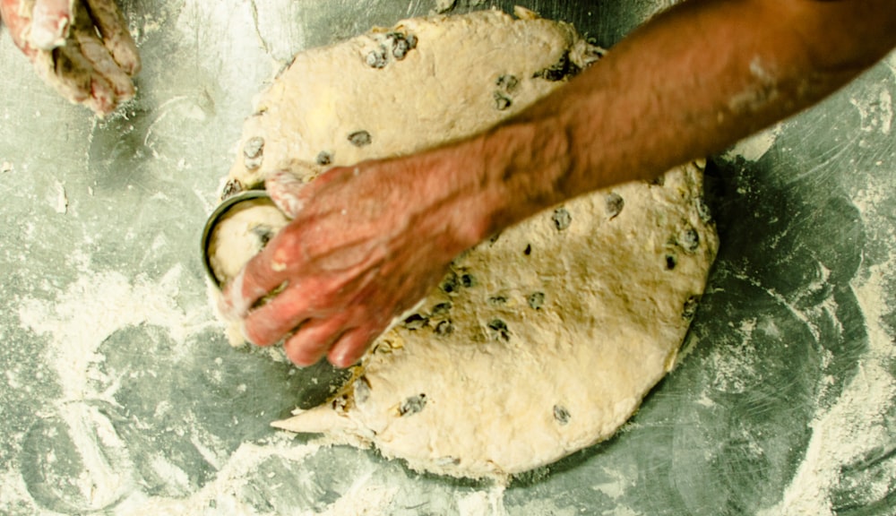 person holding white dough on gray table