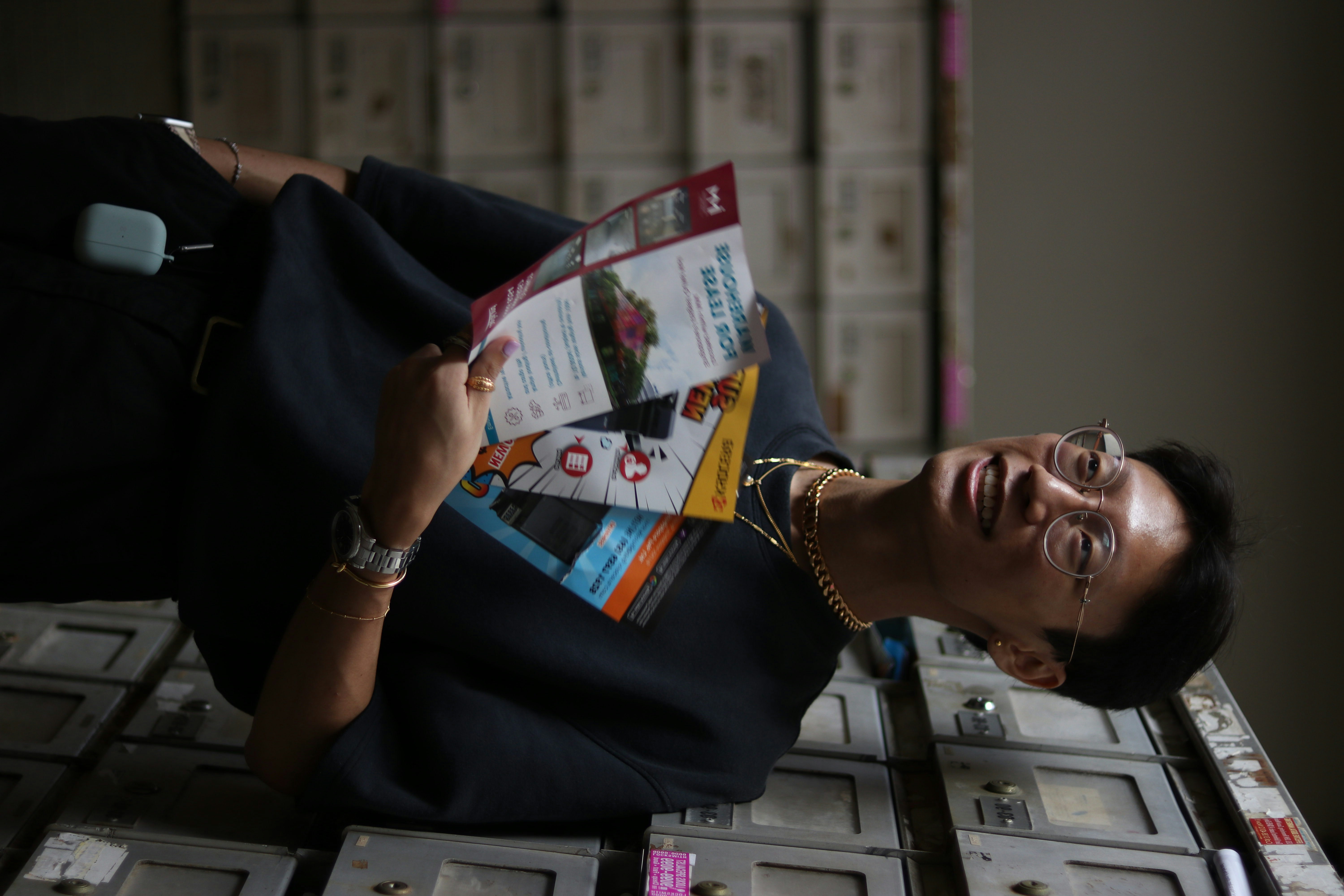 Wanita dengan kemeja leher kru hitam dan kuning memegang kertas printer putih