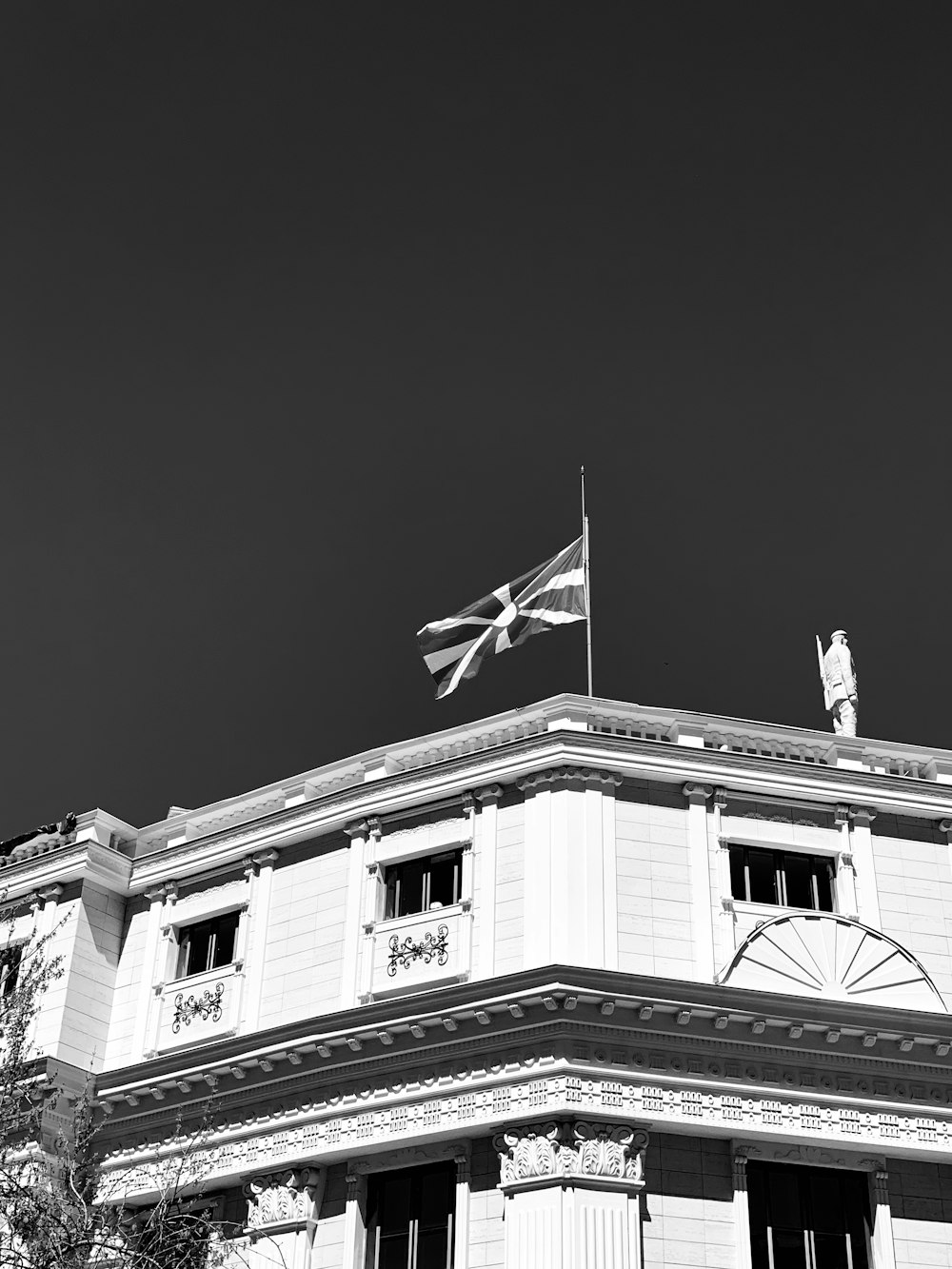 Foto en escala de grises del edificio con la bandera en la parte superior