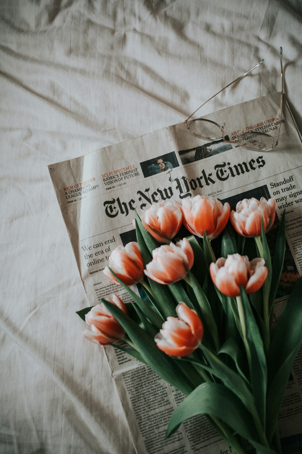 pink tulips on newspaper on white textile