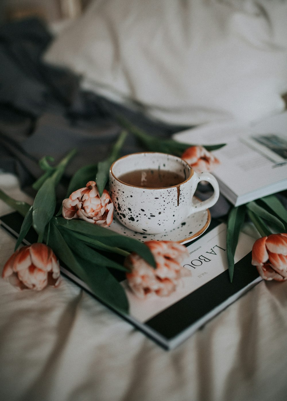 white and red floral ceramic teacup on white book