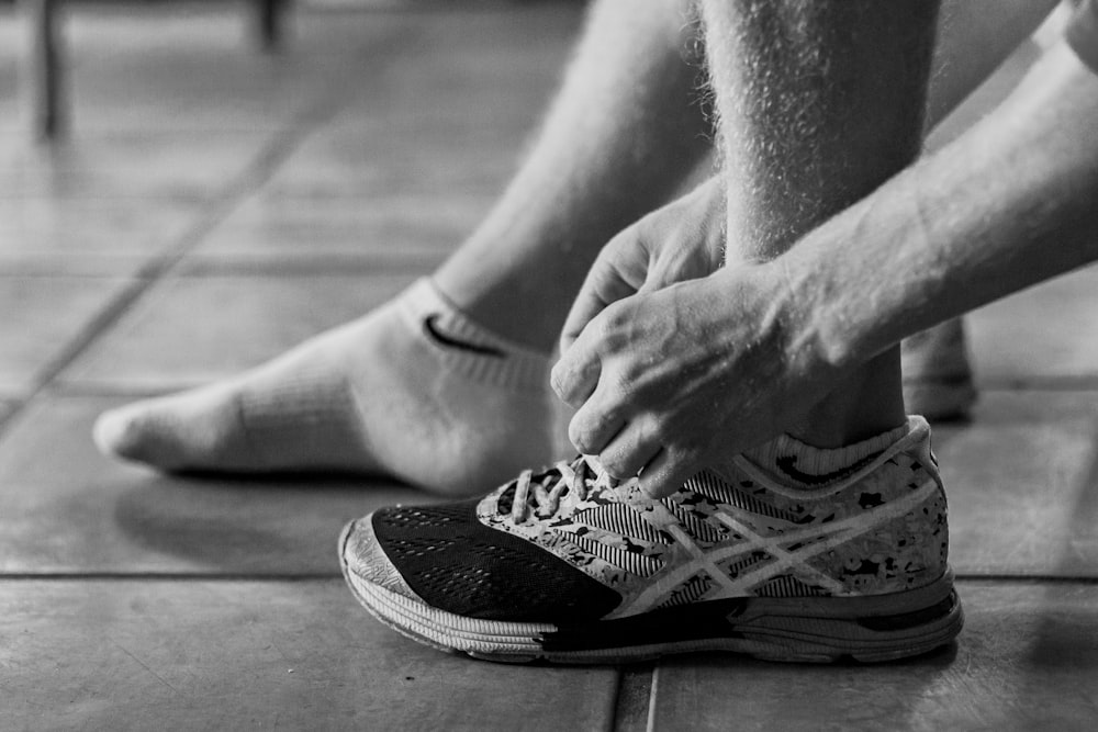 Foto in scala di grigi di una persona che indossa scarpe da ginnastica Nike