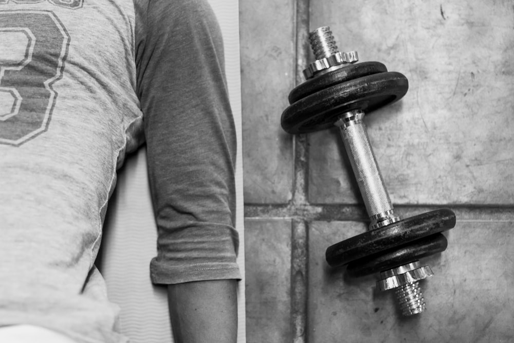 person in black pants and black socks holding dumbbell