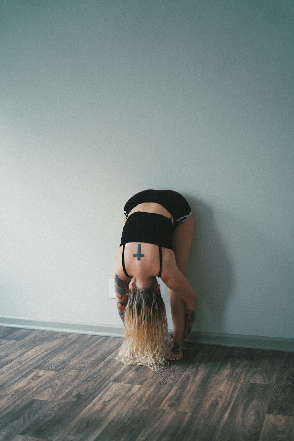 woman in black brassiere leaning on white wall