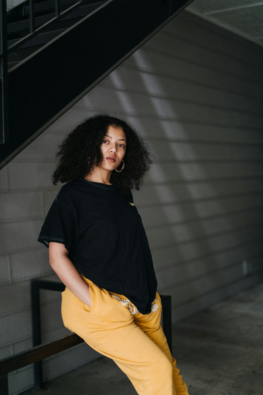 woman in black t-shirt and yellow skirt standing in front of gray wall