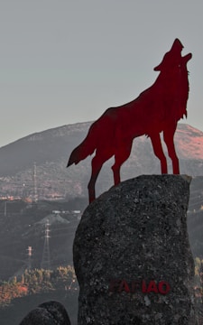A black wolf silhouette howling beneath a blood-red moon.