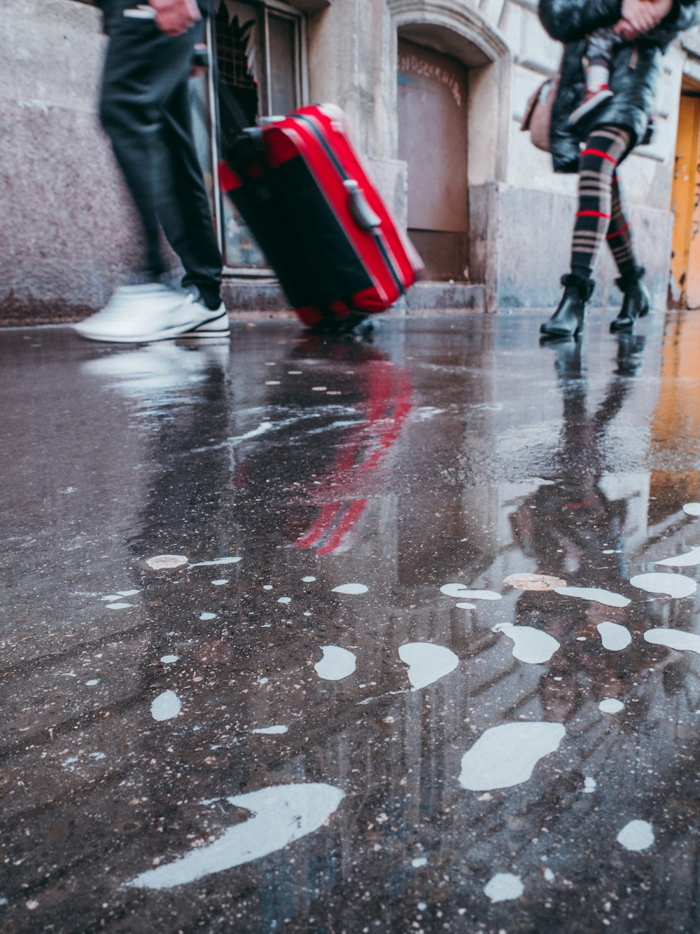 person in black pants walking on wet road