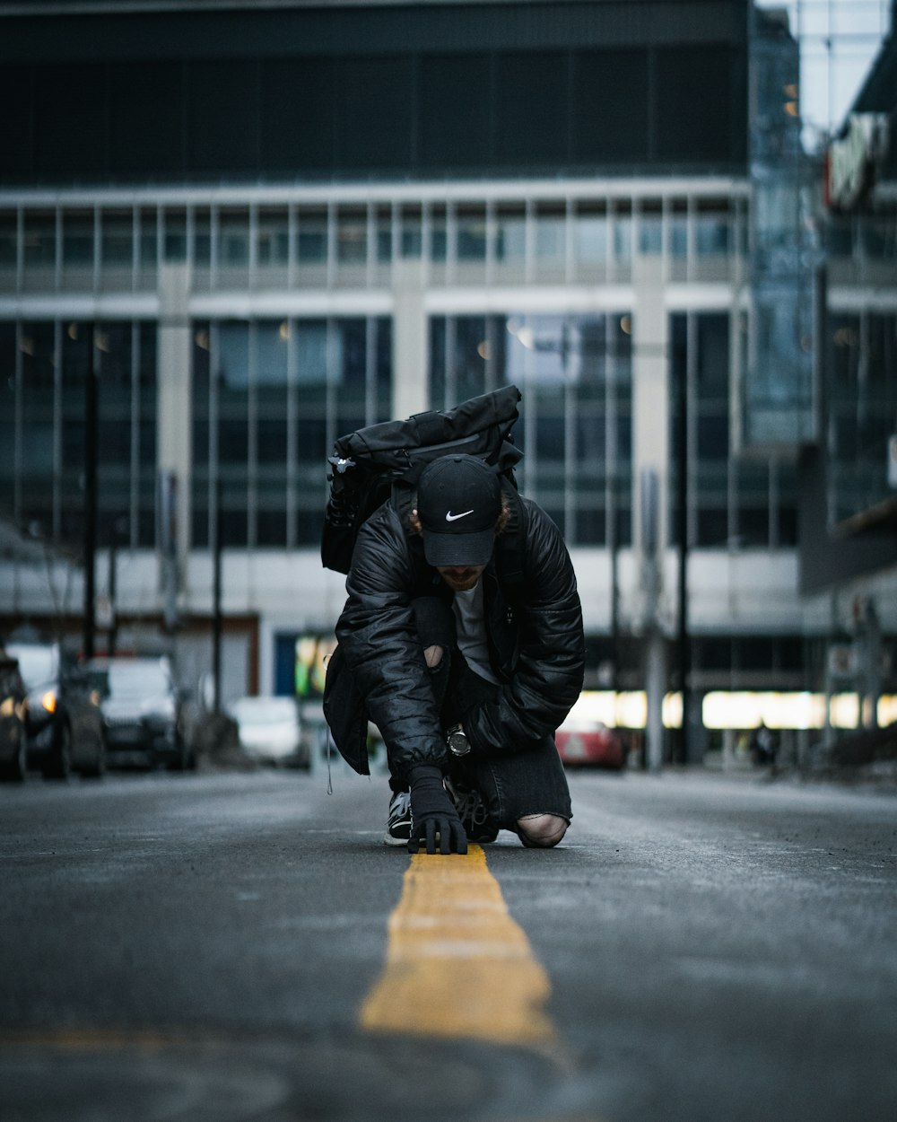 pessoa em jaqueta preta e calças pretas andando na calçada durante o dia