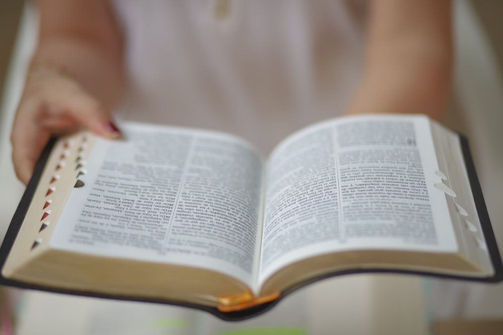 person reading book on brown wooden table