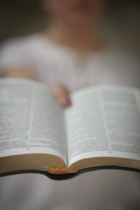 Close-up of a focused person holding an open ebook with intense determination in their eyes.
