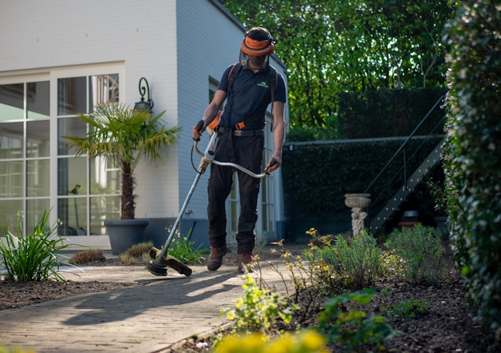 man in black t-shirt and blue denim jeans holding shovel