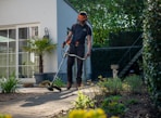 man in black t-shirt and blue denim jeans holding shovel
