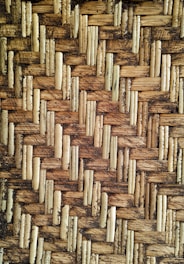 Detailed texture of a woven pattern made from interlaced natural fibers, showcasing an intricate and rustic design.