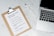 A marble surface displays a clipboard holding a paper with a list titled 'Projects you could start today!', placed next to an open laptop and a pen. The list suggests ideas like creating an online shop or a useful app.