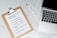 A marble surface displays a clipboard holding a paper with a list titled 'Projects you could start today!', placed next to an open laptop and a pen. The list suggests ideas like creating an online shop or a useful app.