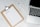 A clipboard with a blank payments checklist is placed on a marble surface next to an open laptop and a white pen. The setup appears to be organized for financial planning or administrative work.