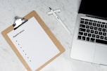 white paper on brown folder beside silver laptop computer