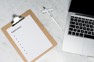 white paper on brown folder beside silver laptop computer