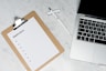 white paper on brown folder beside silver laptop computer
