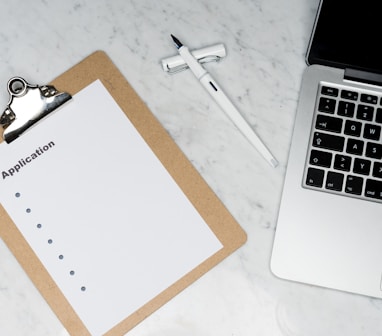 white paper on brown folder beside silver laptop computer