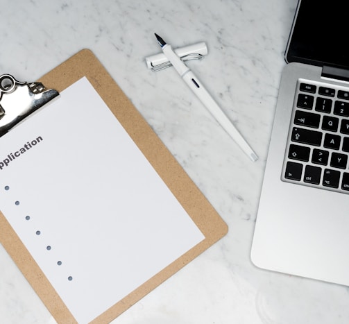 white paper on brown folder beside silver laptop computer