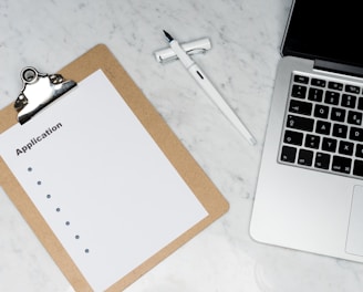 white paper on brown folder beside silver laptop computer