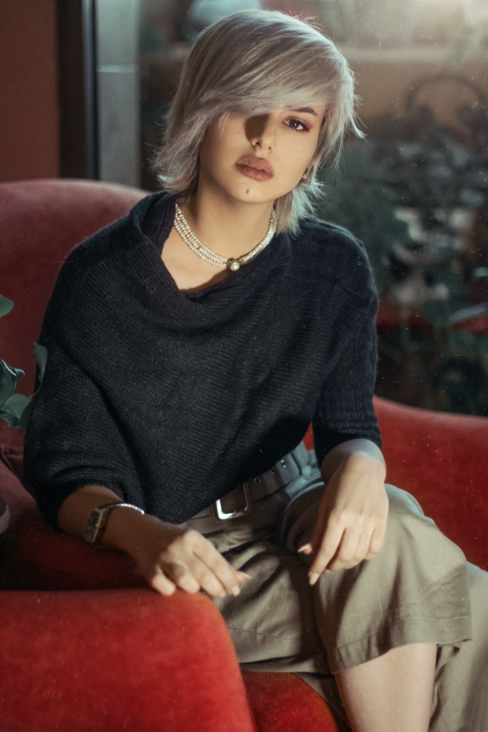 woman in black sweater sitting on red chair