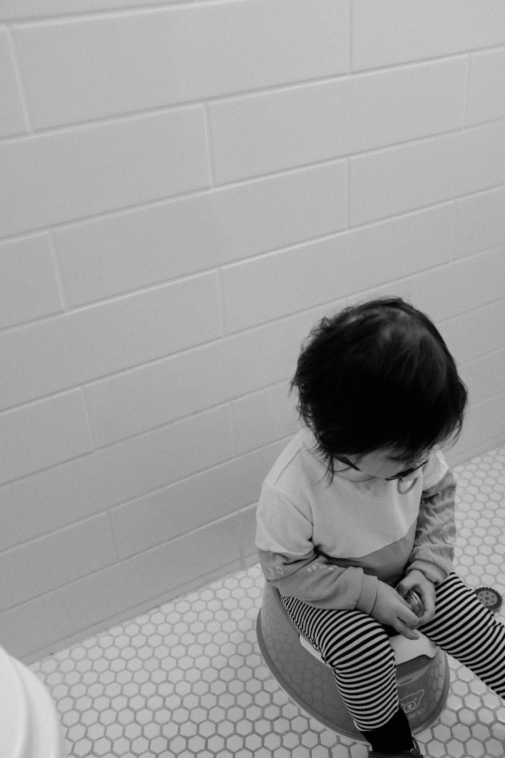 grayscale photo of child in white long sleeve shirt sitting on floor