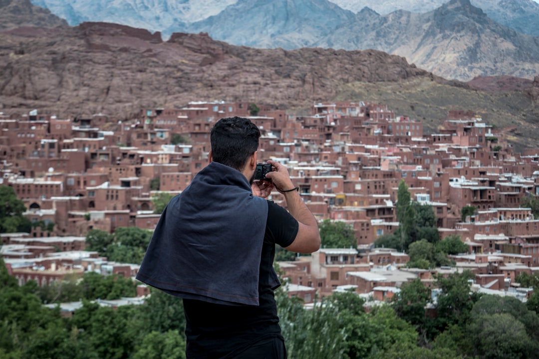 man in grey shirt standing on top of building looking at the city during daytime