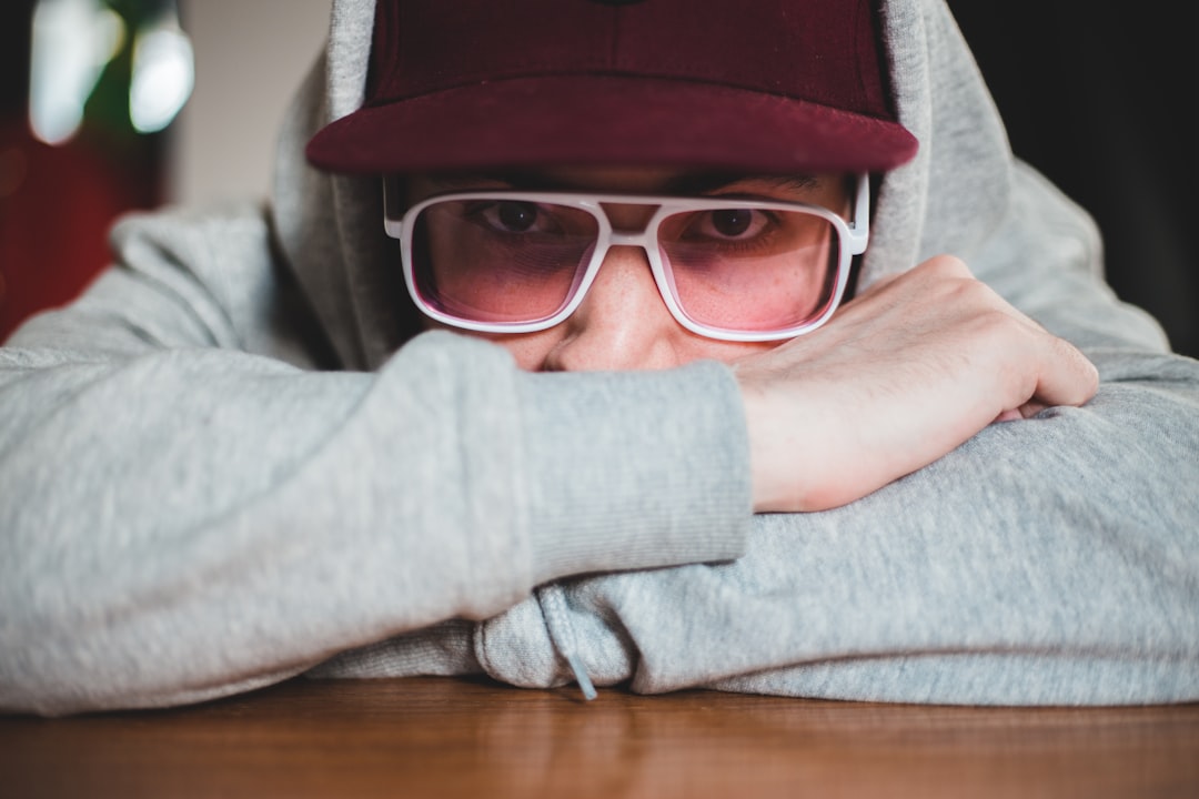 man in gray sweater wearing black framed eyeglasses and brown hat