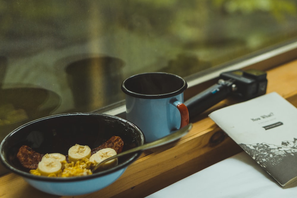 black ceramic mug beside blue ceramic plate on brown wooden table