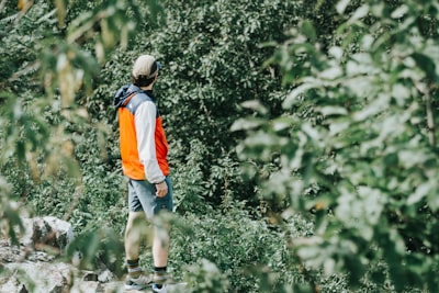 man in orange and white shirt walking on dirt road during daytime virginia teams background