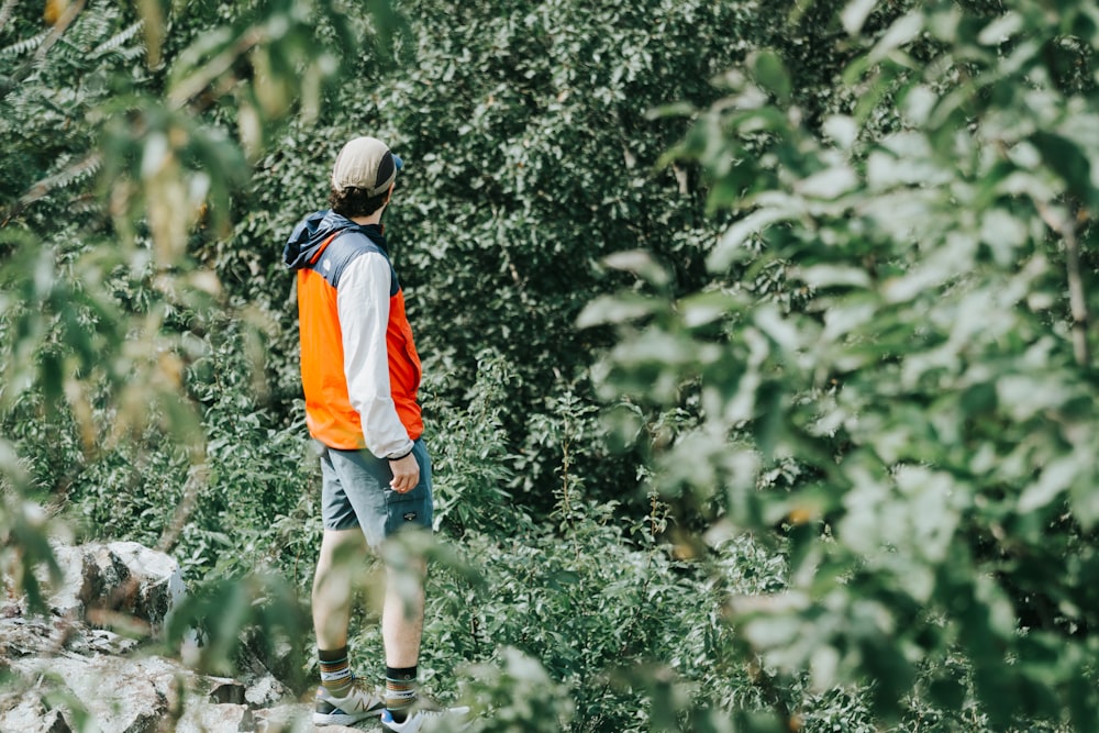 man in orange and white shirt walking on dirt road during daytime