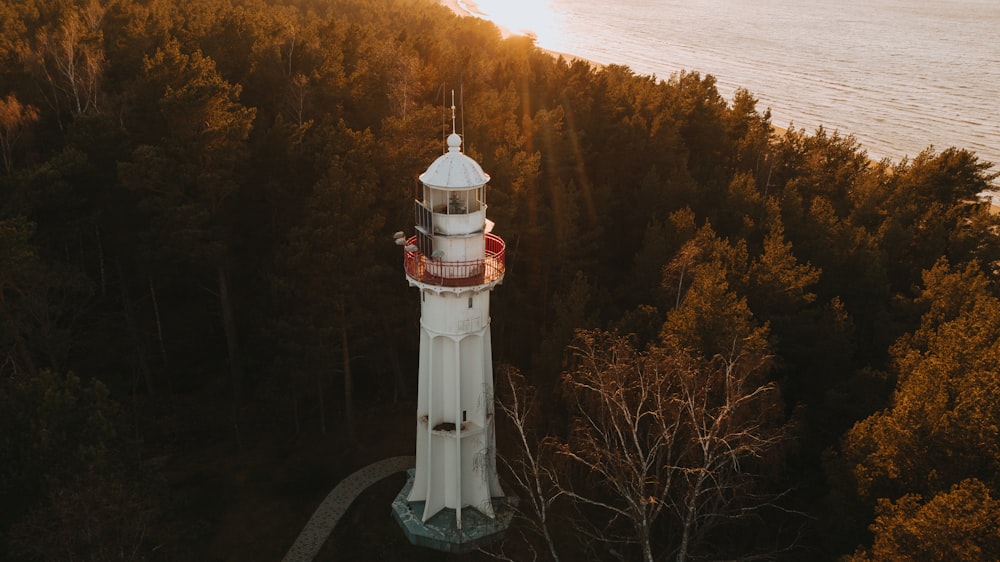 white and red lighthouse near trees during daytime