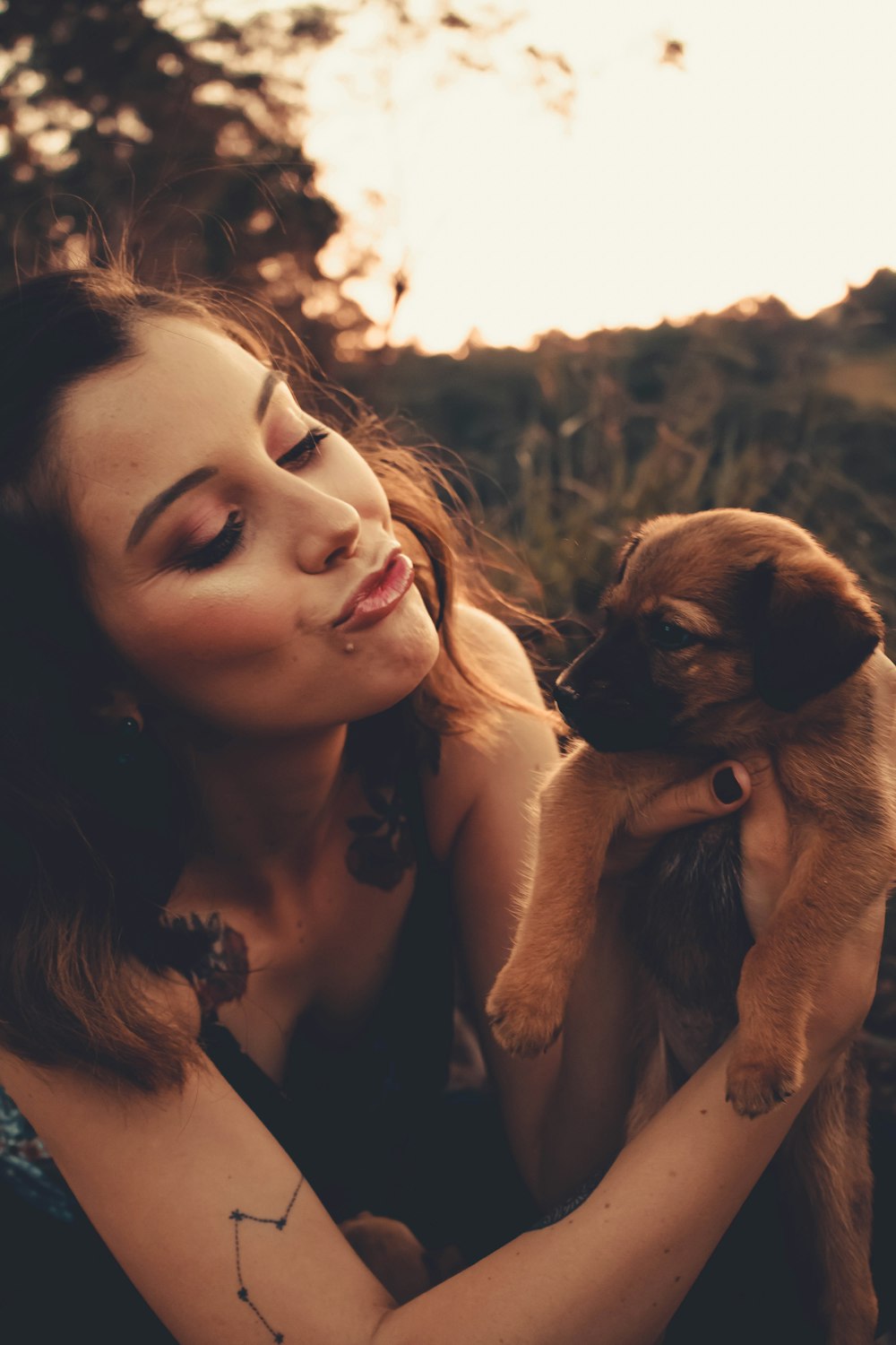 woman holding brown short coated puppy during daytime