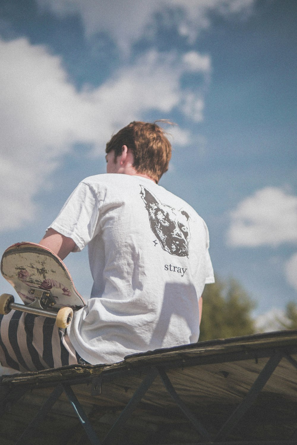 woman in white and black crew neck t-shirt sitting on white chair during daytime