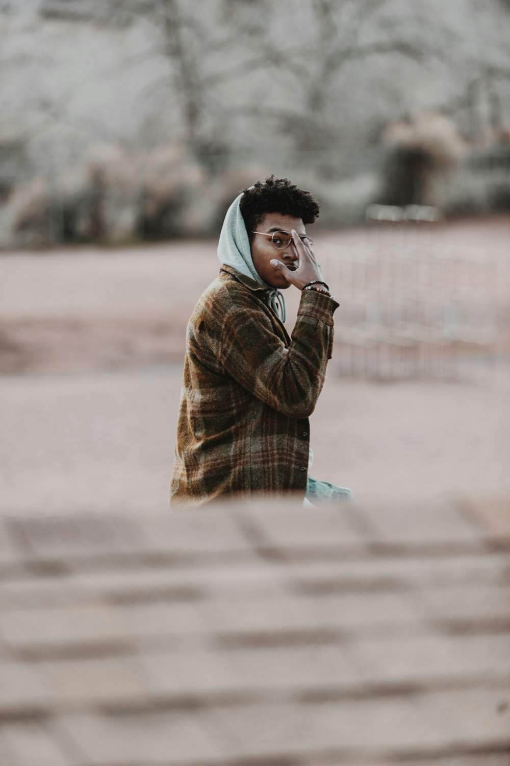 boy in brown jacket standing on road during daytime