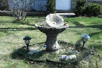 An upcycled bird bath made from vintage ceramics, nestled among blooming garden flowers.