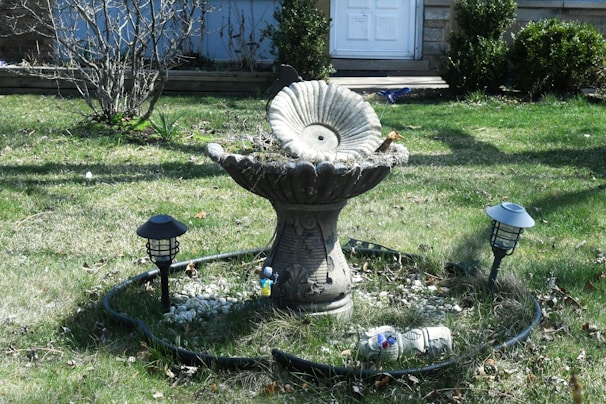 An upcycled bird bath made from vintage ceramics, nestled among blooming garden flowers.