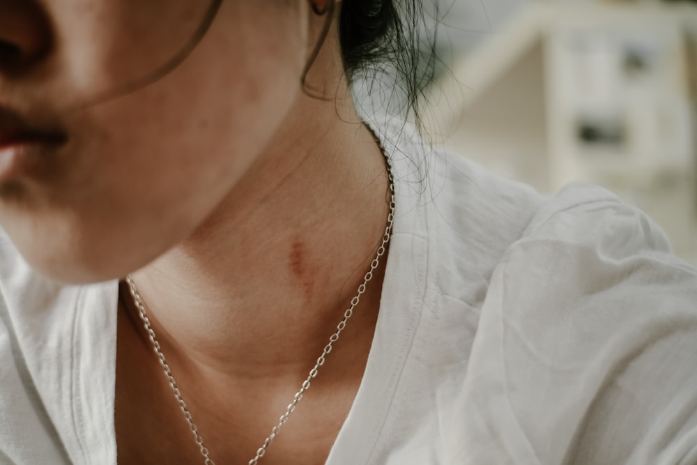 woman in white crew neck shirt wearing gold necklace