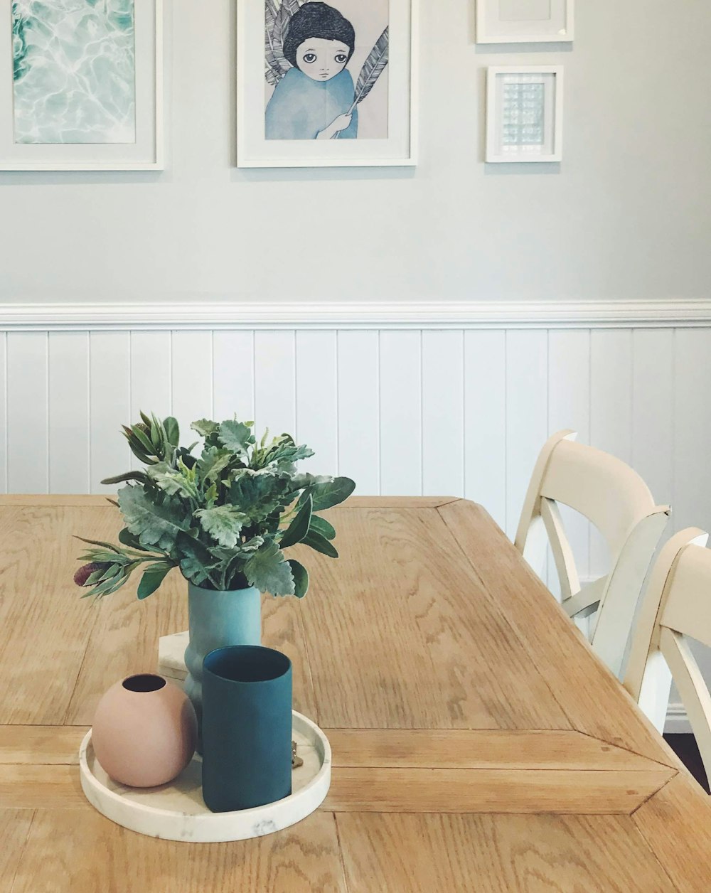 grüne Pflanze auf blauer Keramikvase auf braunem Holztisch