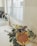 A kitchen sink area with a gold-colored faucet is complemented by a bouquet of flowers on the counter. The window behind the sink allows natural light to brighten the white-tiled backsplash and countertop. A soap dispenser is visible next to the faucet.