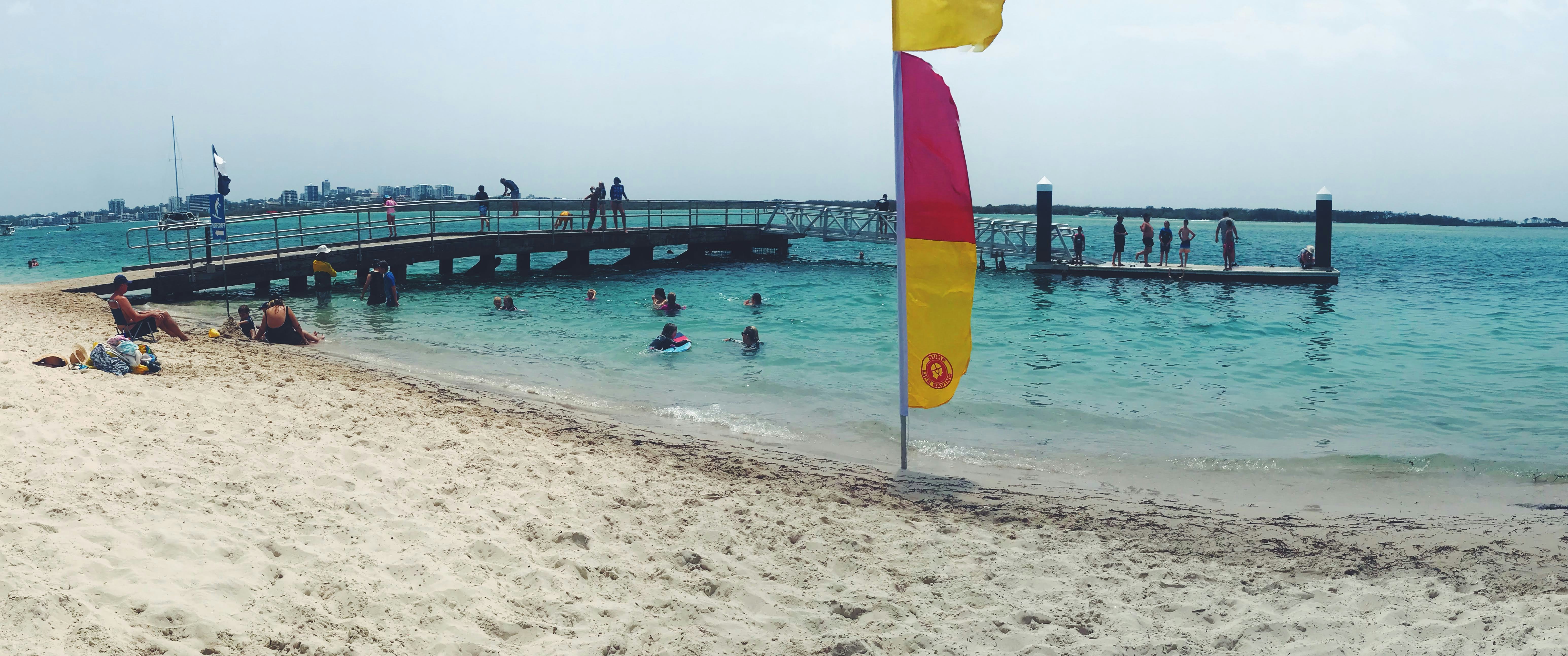 people swimming on beach during daytime