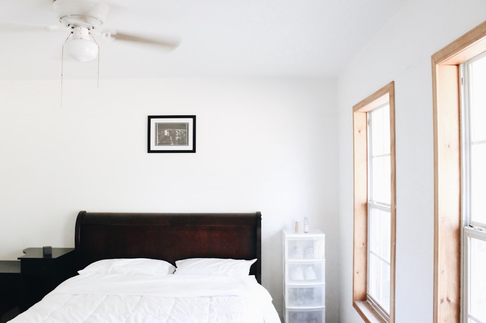 white bed linen near brown wooden cabinet