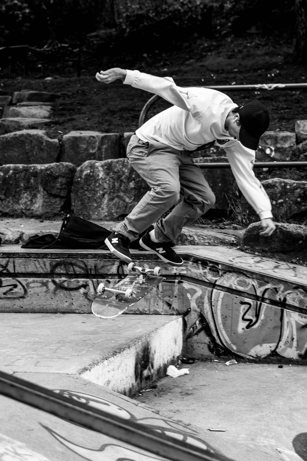 man in white t-shirt and black pants doing skateboard stunts on black metal railings