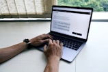 A close-up of hands typing on a laptop with training materials nearby.
